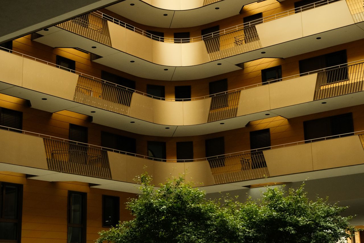 about-01 Contemporary residential building with multiple balconies and lush greenery.