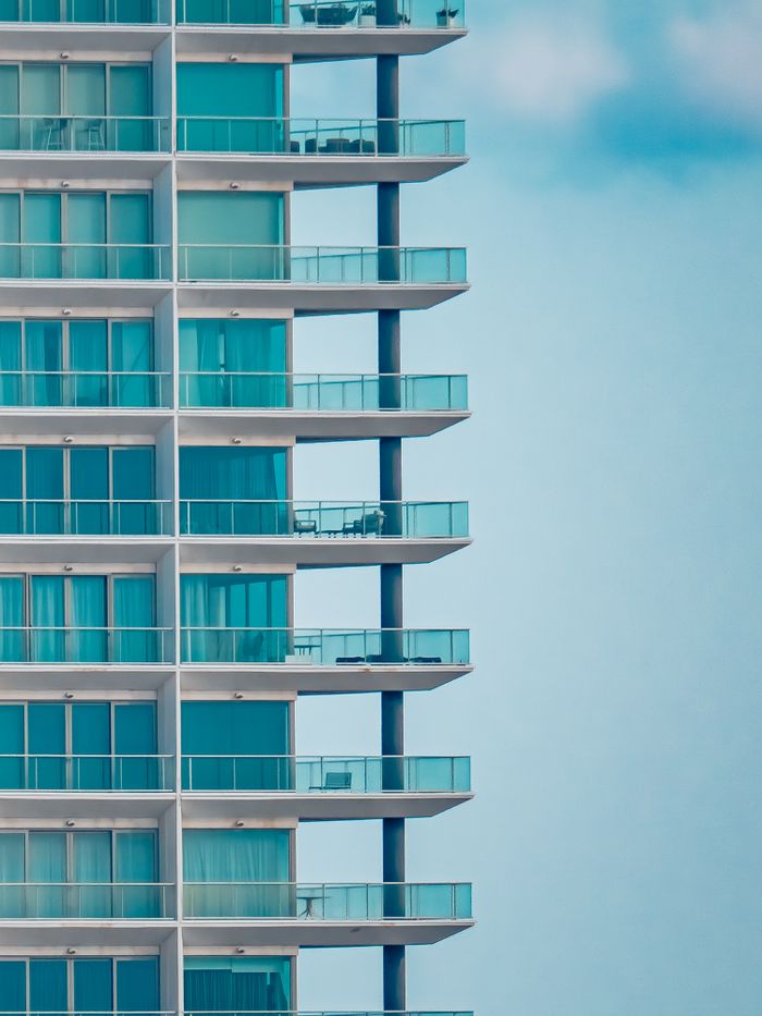 home-services-02 Close-up of a luxurious glass facade on a modern high-rise residential building with balconies.